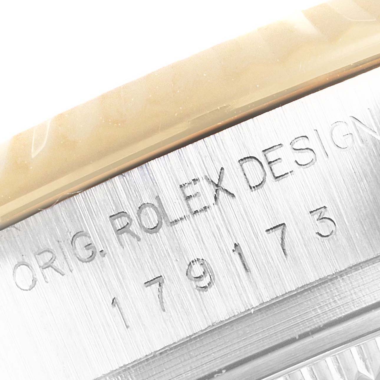 The image shows a close-up of the serial number and engravings, "ORIG. ROLEX DESIGN," on the side of a Rolex Datejust 179173 Women's Steel and Gold (two tone) Champagne Dial 179173 Women's Steel and Gold (two tone) Champagne Dial.