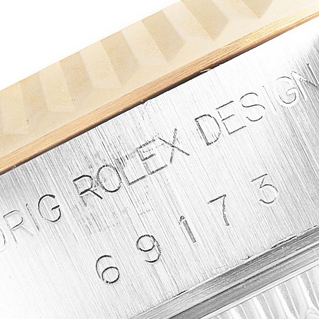 The image shows a close-up angle of a Rolex Datejust 69173 Women's Steel and Gold (two tone) Silver Dial 69173 Women's Steel and Gold (two tone) Silver Dial watch with part of its fluted bezel and engraved case serial number visible.