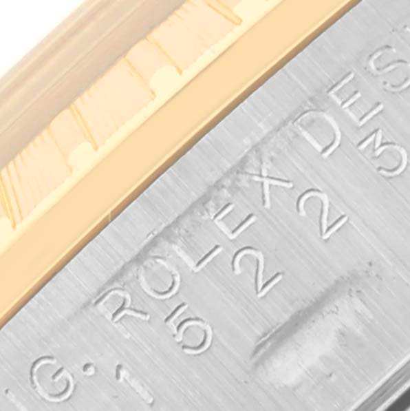 The image shows a close-up of the Rolex Date 15223 Men's Steel and Gold (two tone) Blue Dial 15223 Men's Steel and Gold (two tone) Blue Dial model, focusing on the engraved part of the case and the bezel's edge.