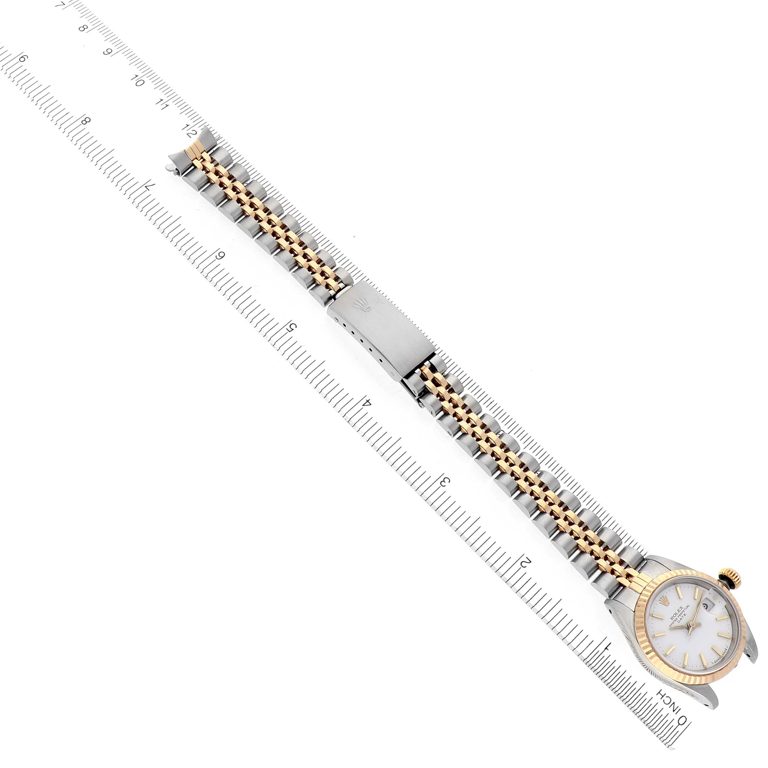 The Rolex Date 69173 Women's Steel and Gold (two tone) White Dial 69173 Women's Steel and Gold (two tone) White Dial watch is shown from the top, displaying the face, bracelet, and clasp next to a ruler for scale.