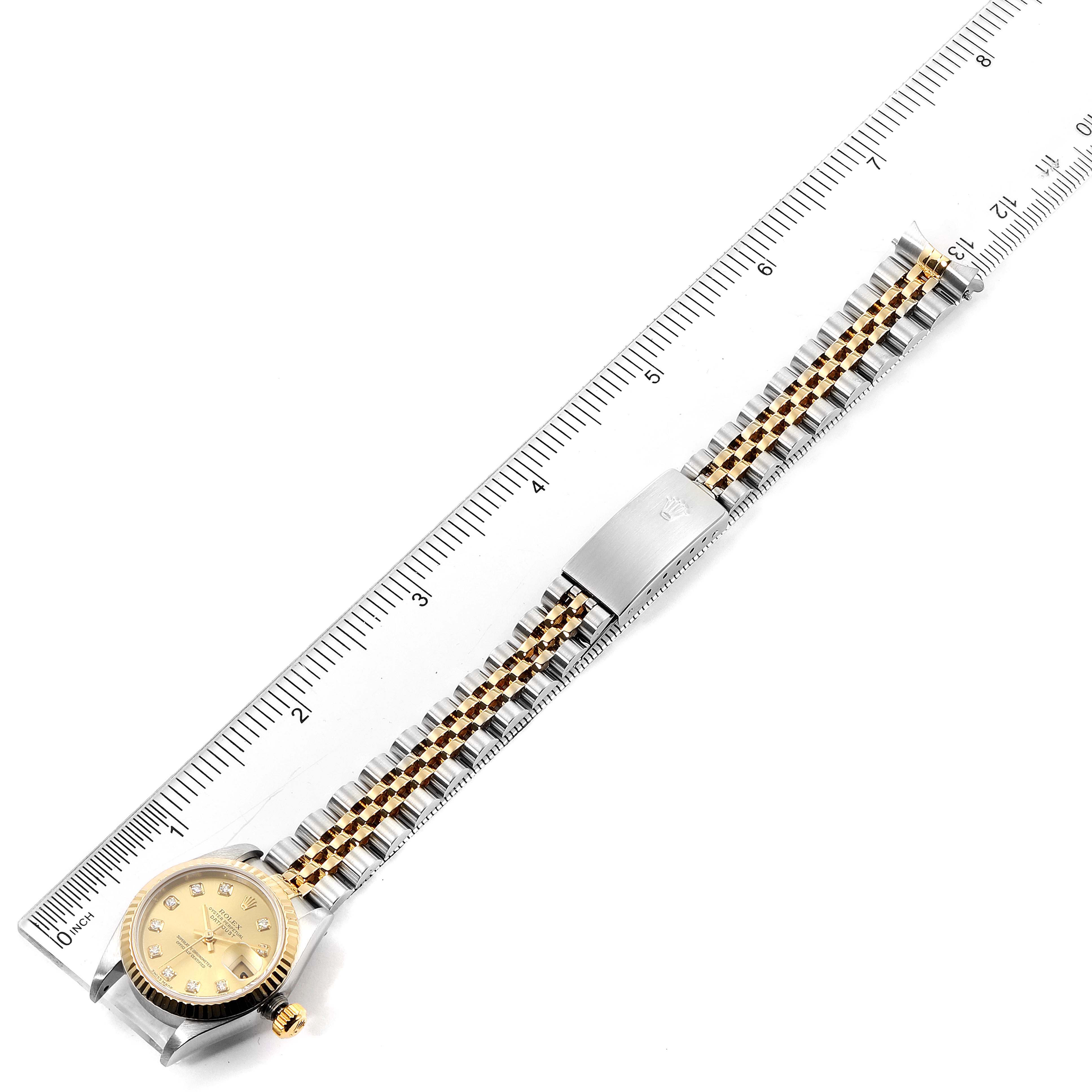 The image shows a top-down view of a Rolex Datejust 79173 Women's Steel and Gold (two tone) Champagne Dial 79173 Women's Steel and Gold (two tone) Champagne Dial watch, displaying its face, bracelet, and clasp, alongside a ruler for scale.