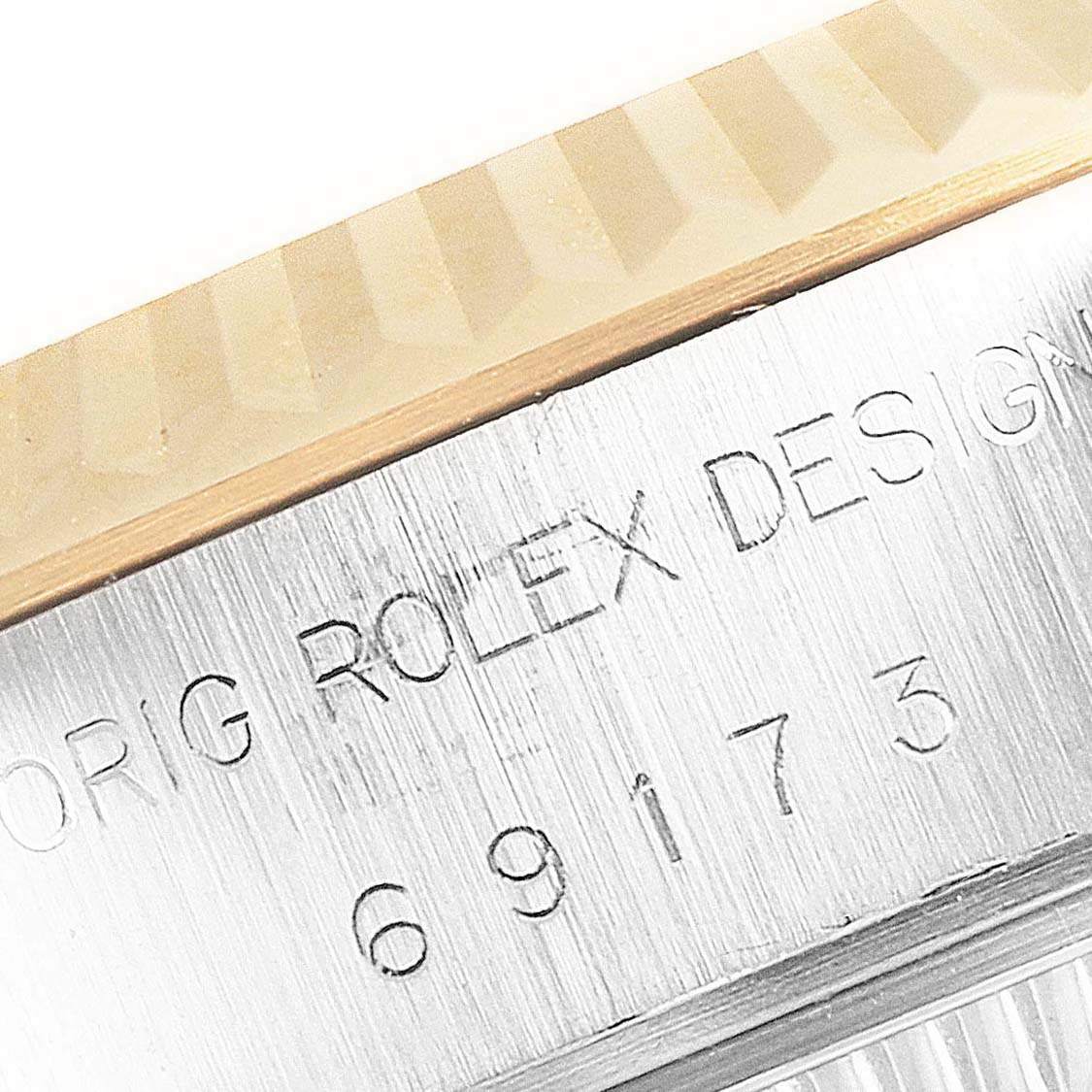 This close-up image of the Rolex Datejust 69173 Women's Steel and Gold (two tone) Silver Dial 69173 Women's Steel and Gold (two tone) Silver Dial shows the fluted bezel and part of the engraved text and serial number.