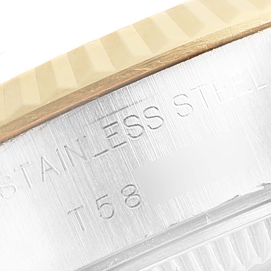 This close-up image of the Rolex Datejust 69173 Women's Steel and Gold (two tone) Silver Dial 69173 Women's Steel and Gold (two tone) Silver Dial watch shows part of the bezel and the stainless steel case with engraved text.