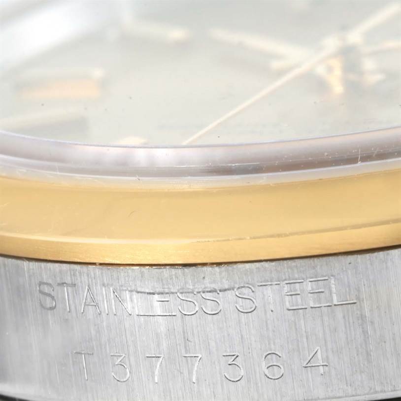 This close-up photo shows the side of the Rolex Oyster Perpetual 14203 Men's Steel and Gold (two tone) Champagne Dial 14203 Men's Steel and Gold (two tone) Champagne Dial watch, highlighting its stainless steel case and engraved serial number.