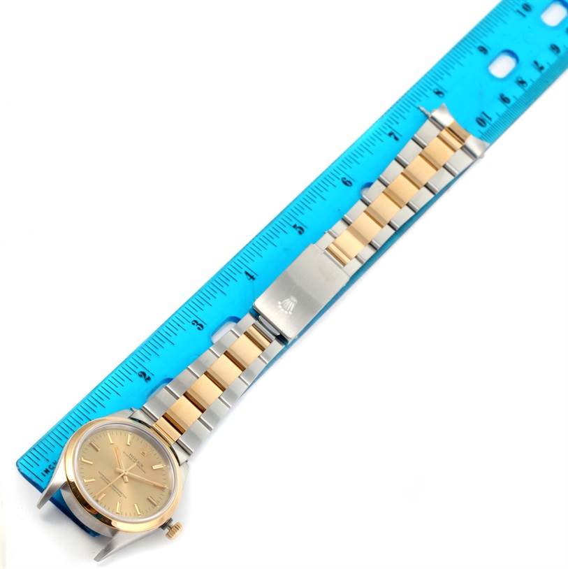 The image shows a top-down view of a Rolex Oyster Perpetual 14203 Men's Steel and Gold (two tone) Champagne Dial 14203 Men's Steel and Gold (two tone) Champagne Dial watch with a two-tone bracelet beside a blue ruler.