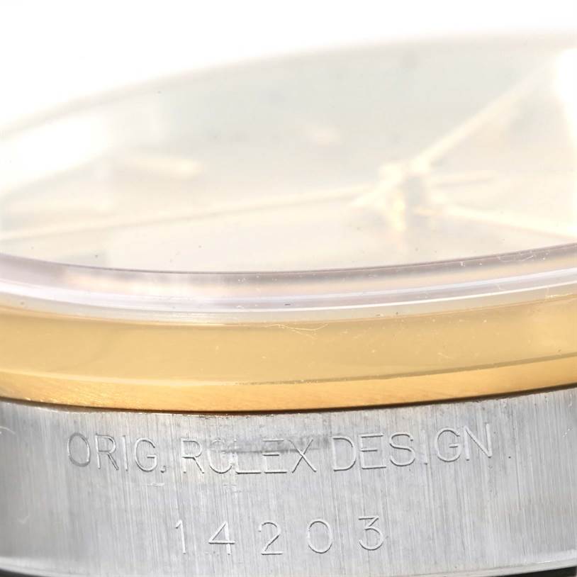This image shows a close-up of the bezel, crystal, and part of the side case of a Rolex Oyster Perpetual 14203 Men's Steel and Gold (two tone) Champagne Dial 14203 Men's Steel and Gold (two tone) Champagne Dial watch, including engraved text.