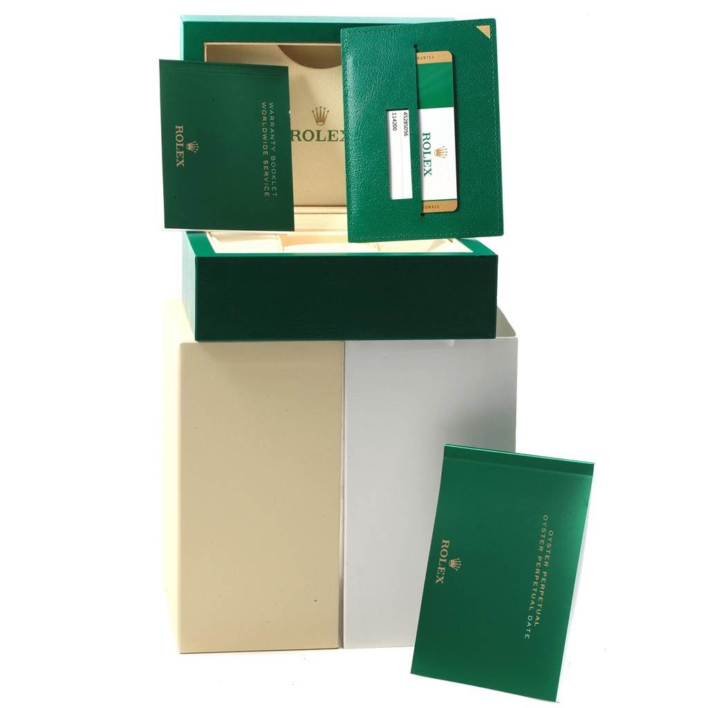 The image shows the packaging and warranty booklet for a Rolex Oyster Perpetual 114200 Men's Stainless Steel Burgundy Dial 114200 Men's Stainless Steel Burgundy Dial watch.