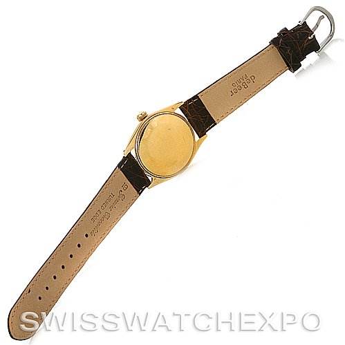 The image shows the back of a Rolex Oyster Perpetual Men's Yellow Gold White Dial Men's Yellow Gold White Dial watch with its leather strap extended and the case back visible.