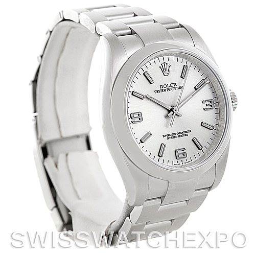 The Rolex Oyster Perpetual 116000 Men's Stainless Steel Silver Dial 116000 Men's Stainless Steel Silver Dial watch is shown at a left-side angle, displaying the face, case, bezel, and part of the bracelet.