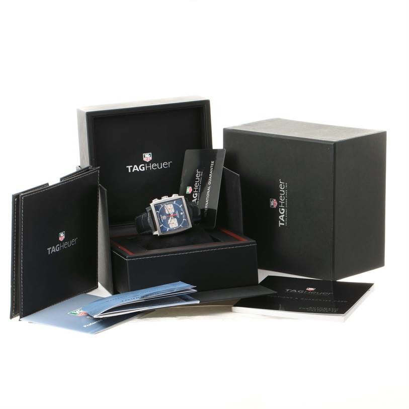 The Tag Heuer Monaco CW2113 Men's Stainless Steel Blue Dial CW2113 Men's Stainless Steel Blue Dial watch and its accessories are displayed in their box with manuals and warranty cards surrounding them.