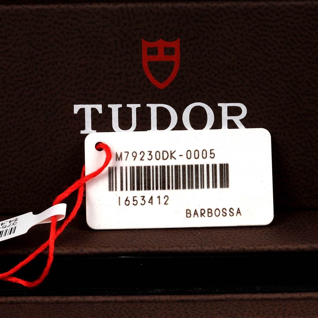 The image shows a close-up of a Tudor Heritage Black Bay 79230DK Men's Stainless Steel Black Dial 79230DK Men's Stainless Steel Black Dial model tag with a barcode and model number.