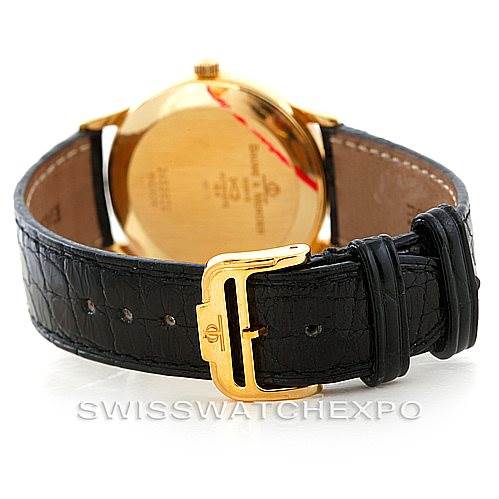 The image shows the Baume & Mercier Classima MV045075 Men's Yellow Gold White Dial MV045075 Men's Yellow Gold White Dial watch from the back, highlighting its gold case and black leather strap with a gold buckle.