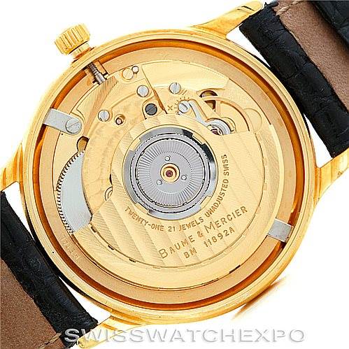 The image shows the back view of a Baume & Mercier Classima MV045075 Men's Yellow Gold White Dial MV045075 Men's Yellow Gold White Dial watch, highlighting its visible automatic movement and rotor.