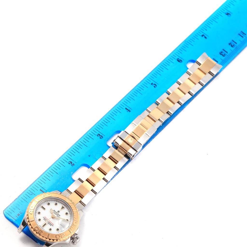The Rolex Yacht-Master 169623 Women's Steel and Gold (two tone) White Dial 169623 Women's Steel and Gold (two tone) White Dial watch is shown with its case, bezel, and full bracelet laid next to a ruler for measurement.