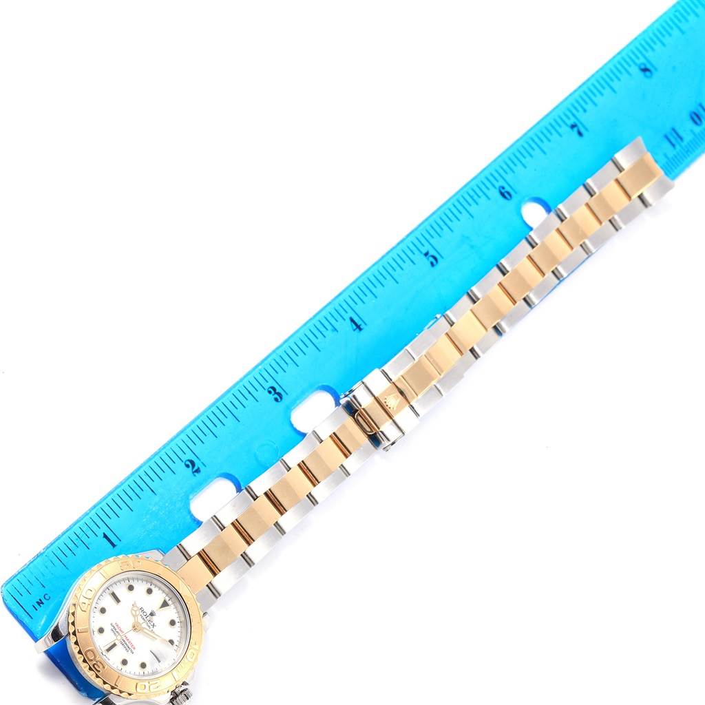 The image shows a Rolex Yacht-Master 169623 Women's Steel and Gold (two tone) White Dial 169623 Women's Steel and Gold (two tone) White Dial watch placed next to a blue ruler, highlighting the bracelet and clasp.
