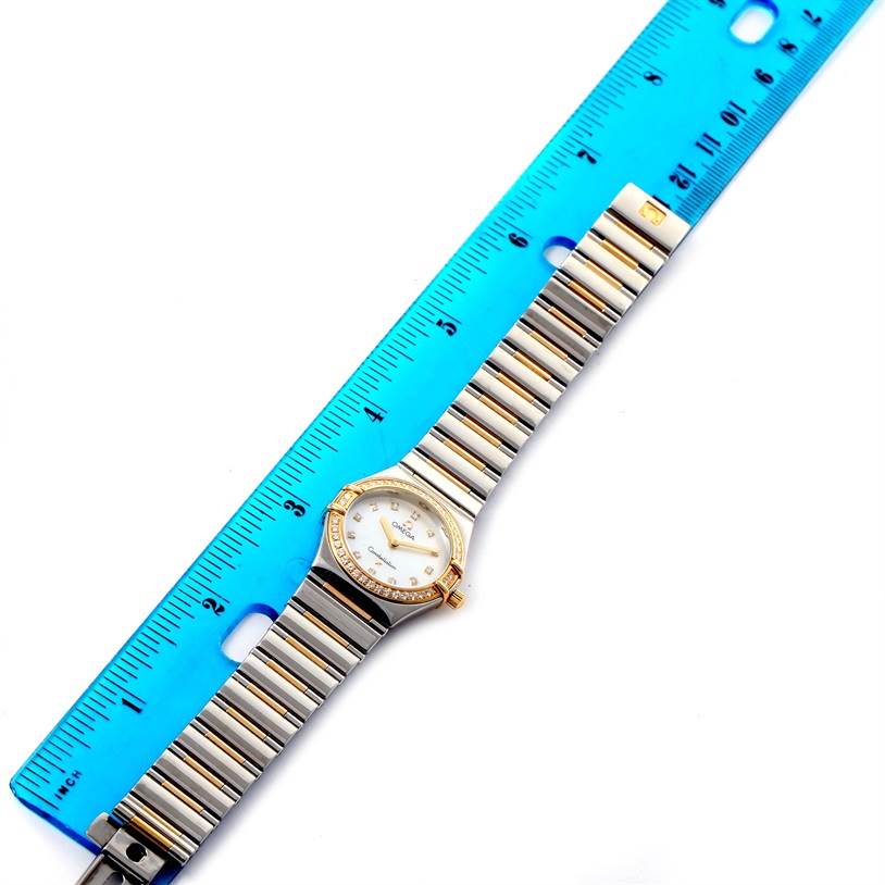 The Omega 1376.75.00 Women's Steel and Gold (two tone) Mother of Pearl Dial 1376.75.00 Women's Steel and Gold (two tone) Mother of Pearl Dial Constellation My Choice 1376.75.00 watch is shown from a top-down angle along with a blue ruler for measurement.