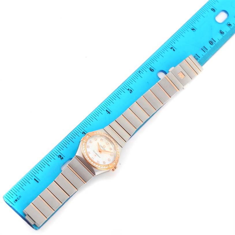 The Omega 123.25.27.60.55.009 Women's Steel and Gold (two tone) Mother of Pearl Dial 123.25.27.60.55.009 Women's Steel and Gold (two tone) Mother of Pearl Dial Constellation Diamond Steel Rose Gold Watch 123.25.27.60.55.009 is shown flat with the entire face and band visible, next to a blue ruler for scale.