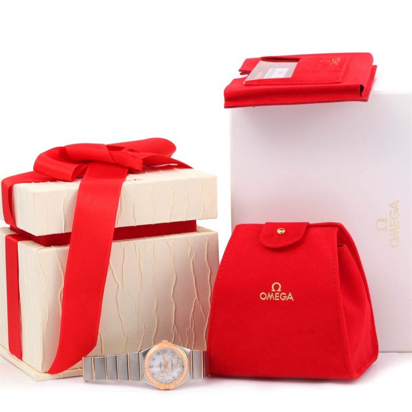 The image shows an Omega 123.25.27.60.55.009 Women's Steel and Gold (two tone) Mother of Pearl Dial 123.25.27.60.55.009 Women's Steel and Gold (two tone) Mother of Pearl Dial Constellation Diamond Steel Rose Gold Watch 123.25.27.60.55.009 and its packaging accessories from a front angle.