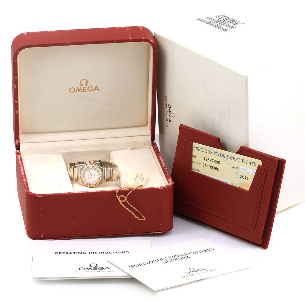 The image shows an Omega 1267.75.00 Women's Steel and Gold (two tone) Mother of Pearl Dial 1267.75.00 Women's Steel and Gold (two tone) Mother of Pearl Dial Constellation Mini MOP Diamond Ladies Watch 1267.75.00 in its open box, alongside certification and paperwork.