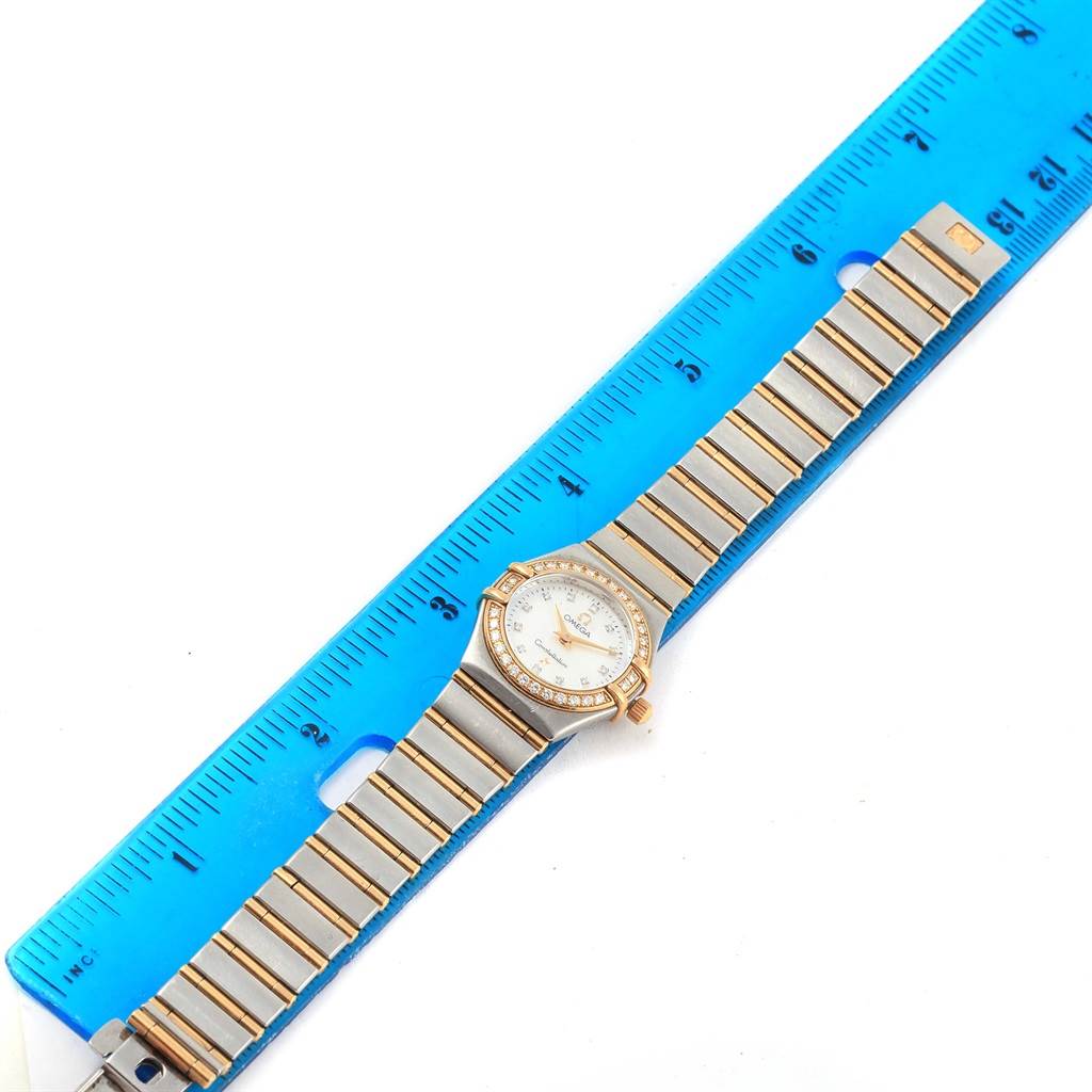 The image shows an Omega 1267.75.00 Women's Steel and Gold (two tone) Mother of Pearl Dial 1267.75.00 Women's Steel and Gold (two tone) Mother of Pearl Dial Constellation Mini MOP Diamond Ladies Watch 1267.75.00 fully extended and measured with a blue ruler.