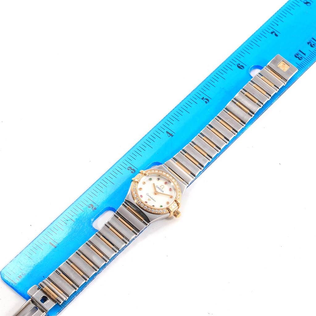 The Omega 1365.79.00 Women's Steel and Gold (two tone) Mother of Pearl Dial 1365.79.00 Women's Steel and Gold (two tone) Mother of Pearl Dial Constellation Iris 1365.79.00 watch is shown from a top-down angle, placed next to a blue ruler for scale.