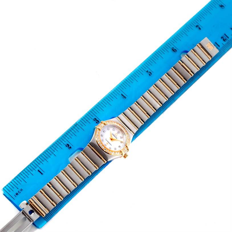 The Omega 1267.75.00 Women's Steel and Gold (two tone) Mother of Pearl Dial 1267.75.00 Women's Steel and Gold (two tone) Mother of Pearl Dial Constellation My Choice Steel Gold Diamond Watch 1267.75.00 is shown laying flat next to a blue ruler.