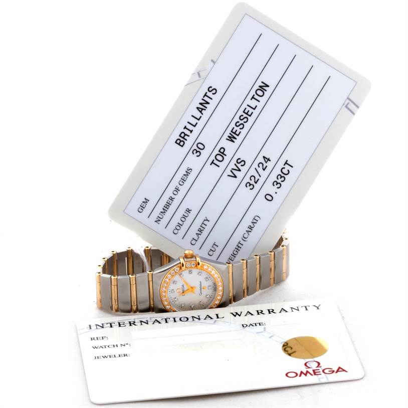 The Omega 1267.75.00 Women's Steel and Gold (two tone) Mother of Pearl Dial 1267.75.00 Women's Steel and Gold (two tone) Mother of Pearl Dial Constellation My Choice Steel Gold Diamond Watch 1267.75.00 is shown laying flat with its warranty and gem certification cards visible.