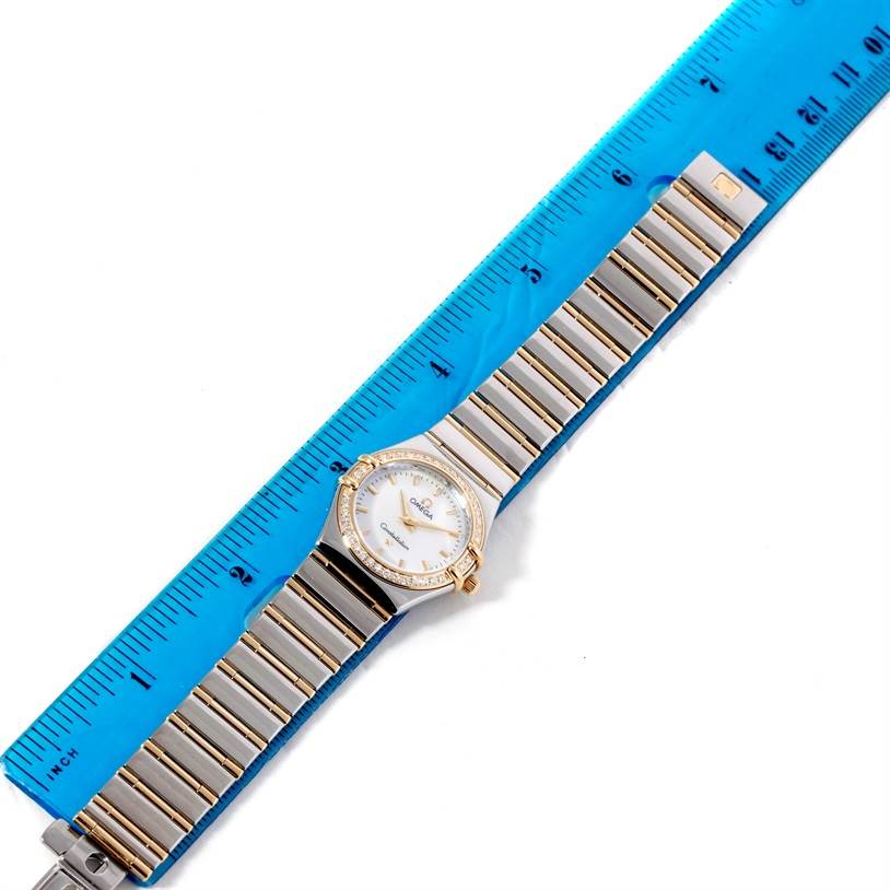 The image shows the face and band of the Omega 1277.70.00 Women's Steel and Gold (two tone) Mother of Pearl Dial 1277.70.00 Women's Steel and Gold (two tone) Mother of Pearl Dial Constellation My Choice Steel Gold Diamond Watch 1277.70.00 with a blue ruler beside it.