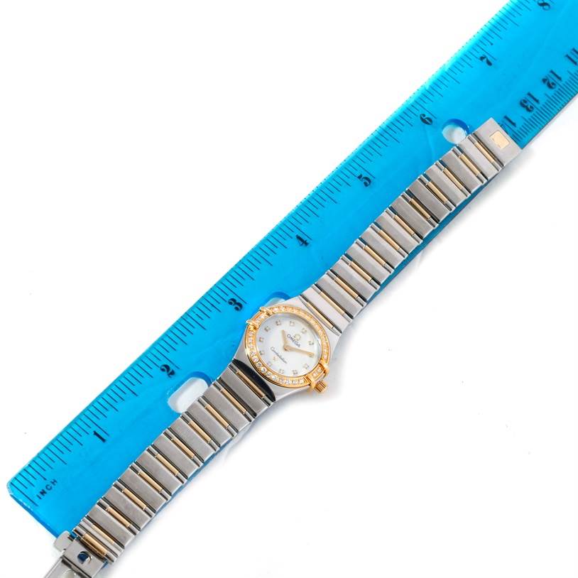 The Omega 1365.71.00 Women's Steel and Gold (two tone) Mother of Pearl Dial 1365.71.00 Women's Steel and Gold (two tone) Mother of Pearl Dial Constellation Mini Steel Yellow Gold Diamond Watch 1365.71.00 is shown from a top-down angle with a blue ruler for scale.