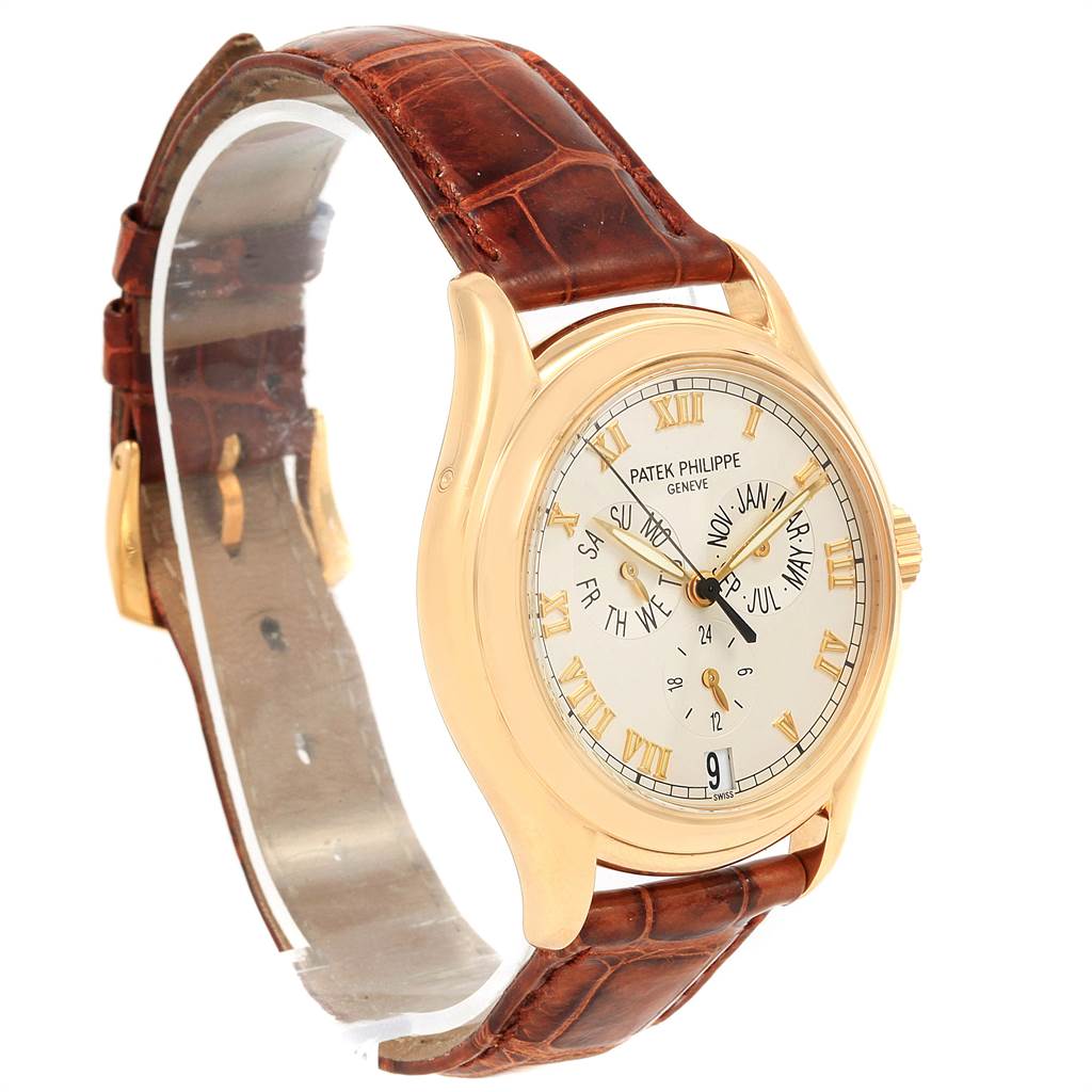 The Patek Philippe 5035J Men's Yellow Gold Silver Dial 5035J Men's Yellow Gold Silver Dial Complicated Annual Calendar 5035 watch is shown at a three-quarter angle, highlighting its yellow gold casing and brown leather strap.