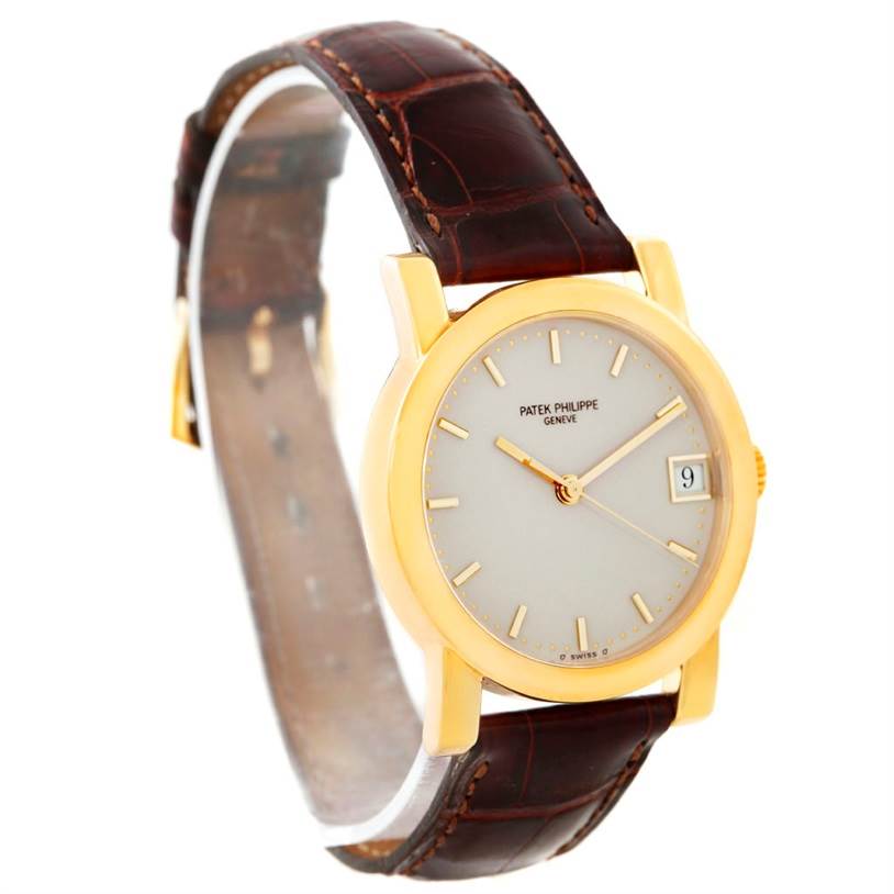 This image shows a Patek Philippe Calatrava 5012 Men's Yellow Gold Beige Dial 5012 Men's Yellow Gold Beige Dial watch at a slight angle highlighting the face, strap, and date display.