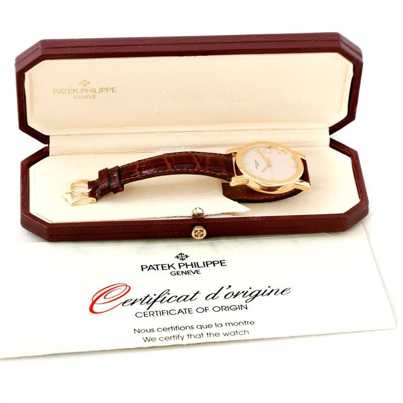 The image shows a Patek Philippe Calatrava 5012 Men's Yellow Gold Beige Dial 5012 Men's Yellow Gold Beige Dial watch angled slightly to display the face and strap, inside its case with a certificate of origin.