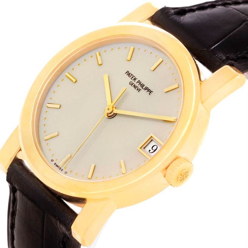 The image shows a close-up of a Patek Philippe Calatrava 5012 Men's Yellow Gold Beige Dial 5012 Men's Yellow Gold Beige Dial watch, featuring its dial, hands, crown, and part of the leather strap.