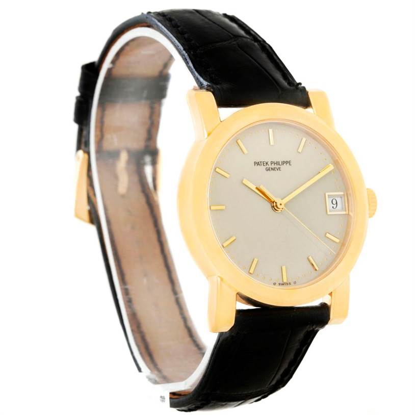 The Patek Philippe Calatrava 5012 Men's Yellow Gold Beige Dial 5012 Men's Yellow Gold Beige Dial watch is shown at a slight angle, displaying the face, date window, and black leather strap.