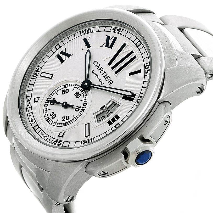 The image shows a Calibre de Cartier watch by Cartier at an oblique angle, highlighting the dial, bracelet, crown, and bezel.