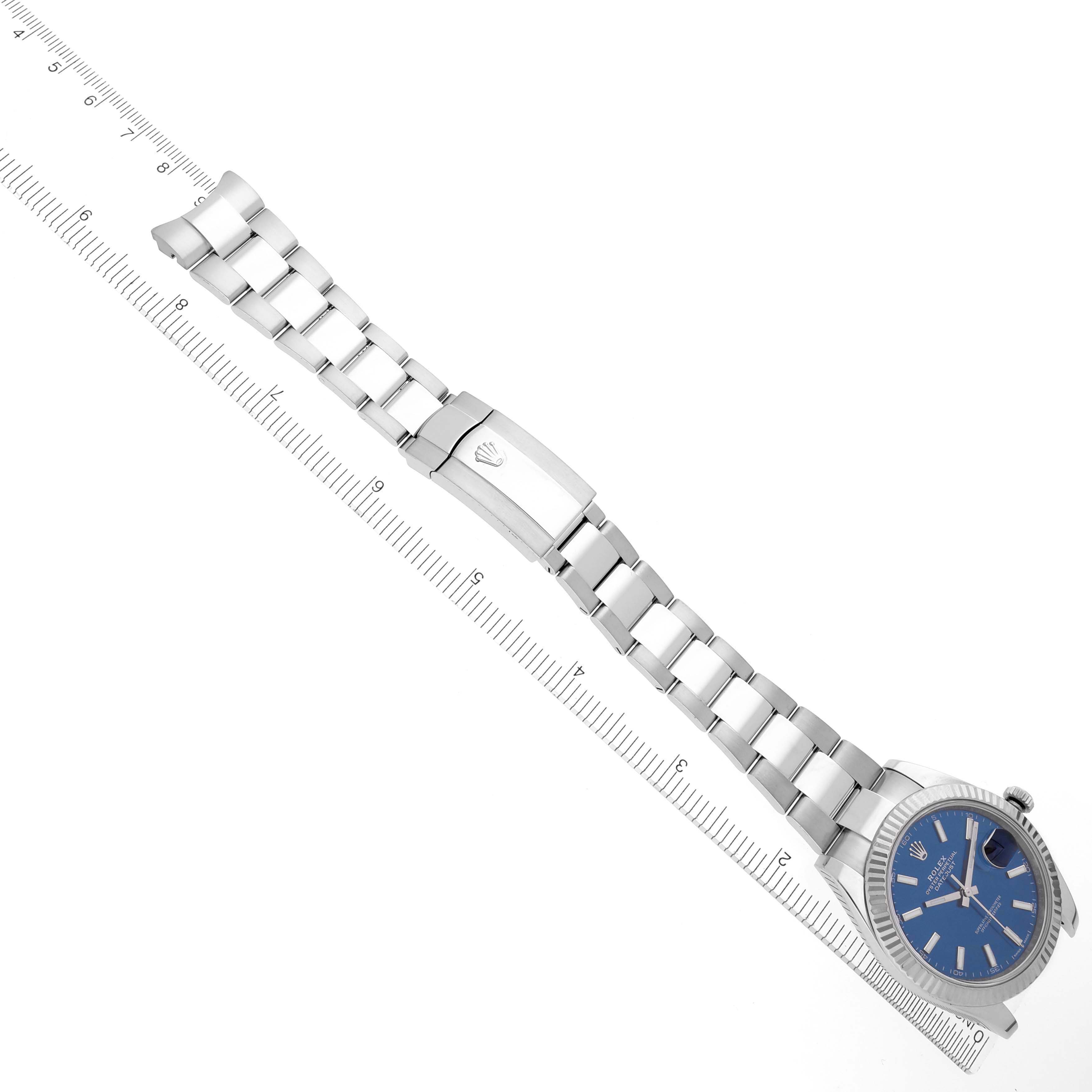 The image shows a top-down view of a Rolex Datejust 41 126334 Men's Stainless Steel Blue Dial 126334 Men's Stainless Steel Blue Dial watch with a blue dial and silver bracelet, accompanied by a ruler.