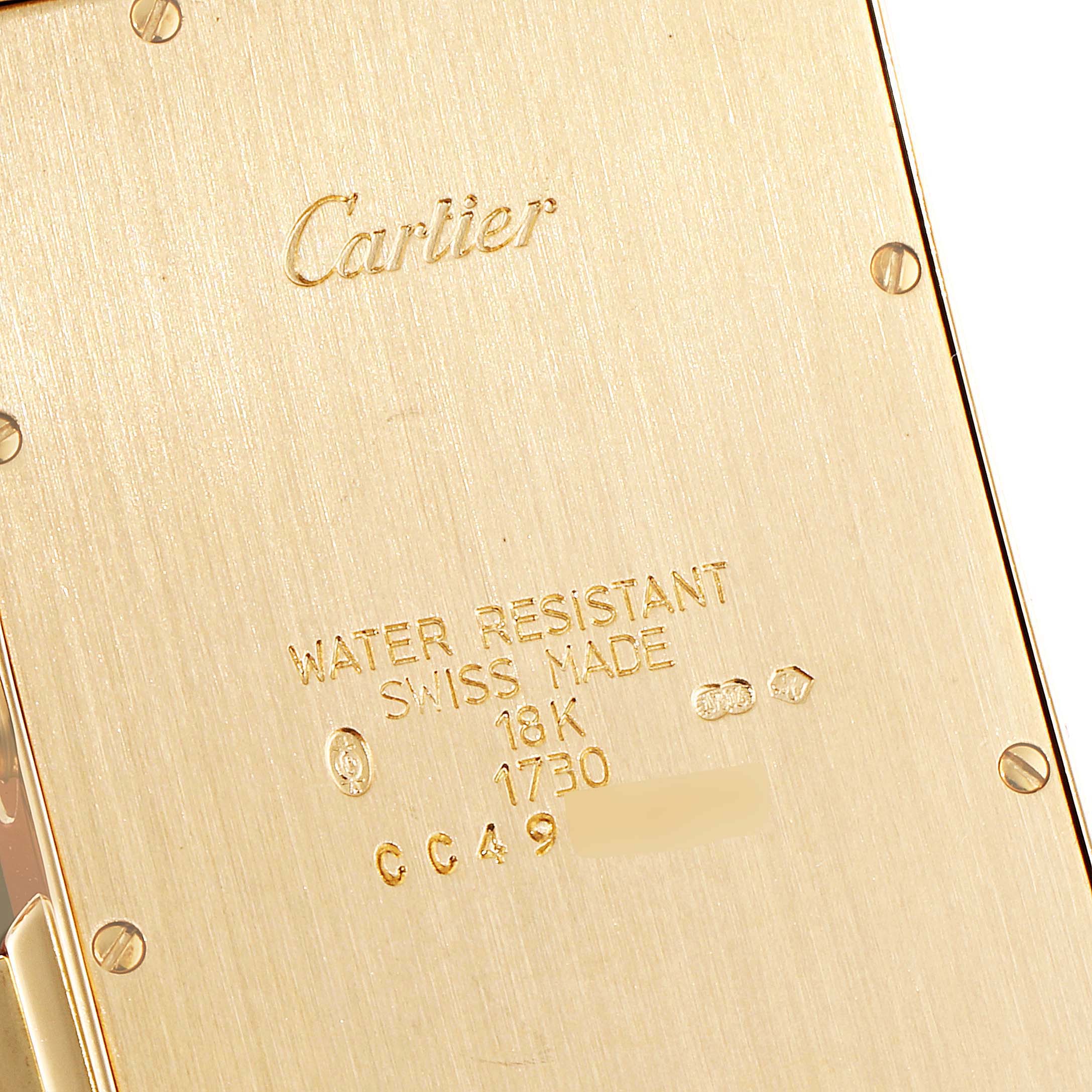 This image shows the back case of a Cartier Tank Americaine W2601156 Men's Yellow Gold Silver Dial W2601156 Men's Yellow Gold Silver Dial watch, highlighting its engravings and gold finish.