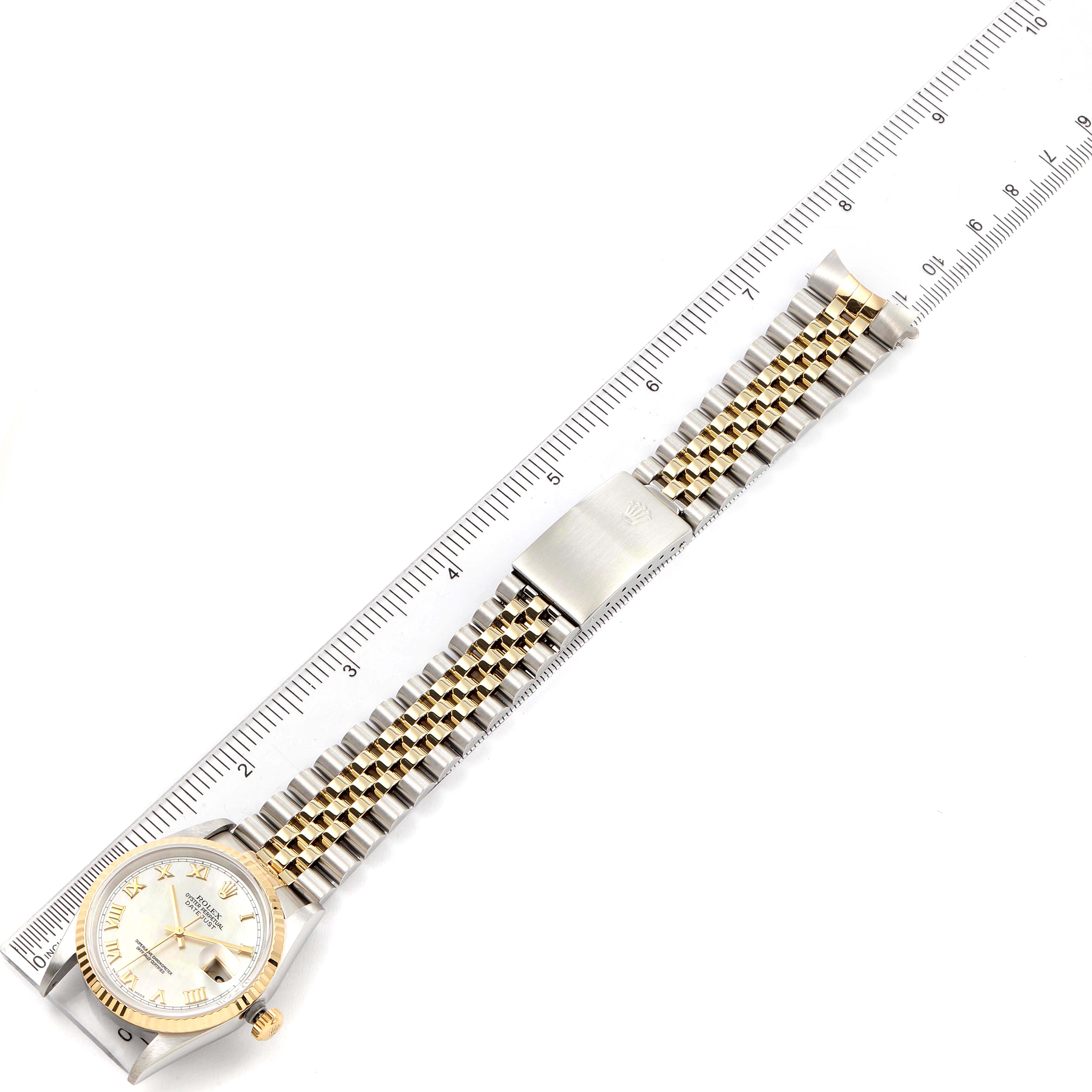 The Rolex Datejust 16233 Men's Steel and Gold (two tone) Mother of Pearl Dial 16233 Men's Steel and Gold (two tone) Mother of Pearl Dial watch is shown fully extended with its face, bezel, and bracelet visible, placed alongside a ruler.