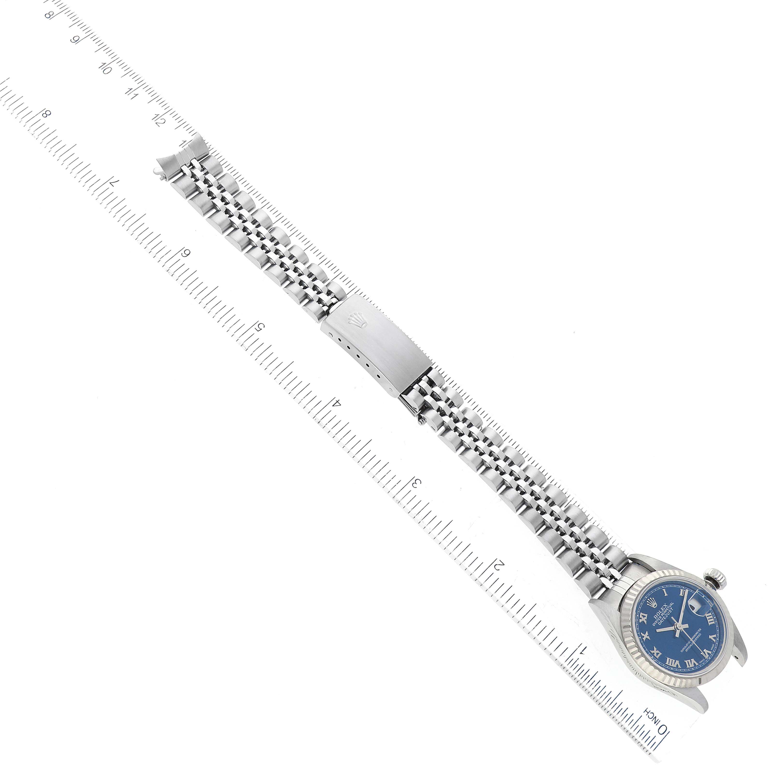 This image shows a Rolex Datejust 79174 Women's Stainless Steel Blue Dial 79174 Women's Stainless Steel Blue Dial watch laid flat with a ruler for measurements, displaying its bracelet and face.