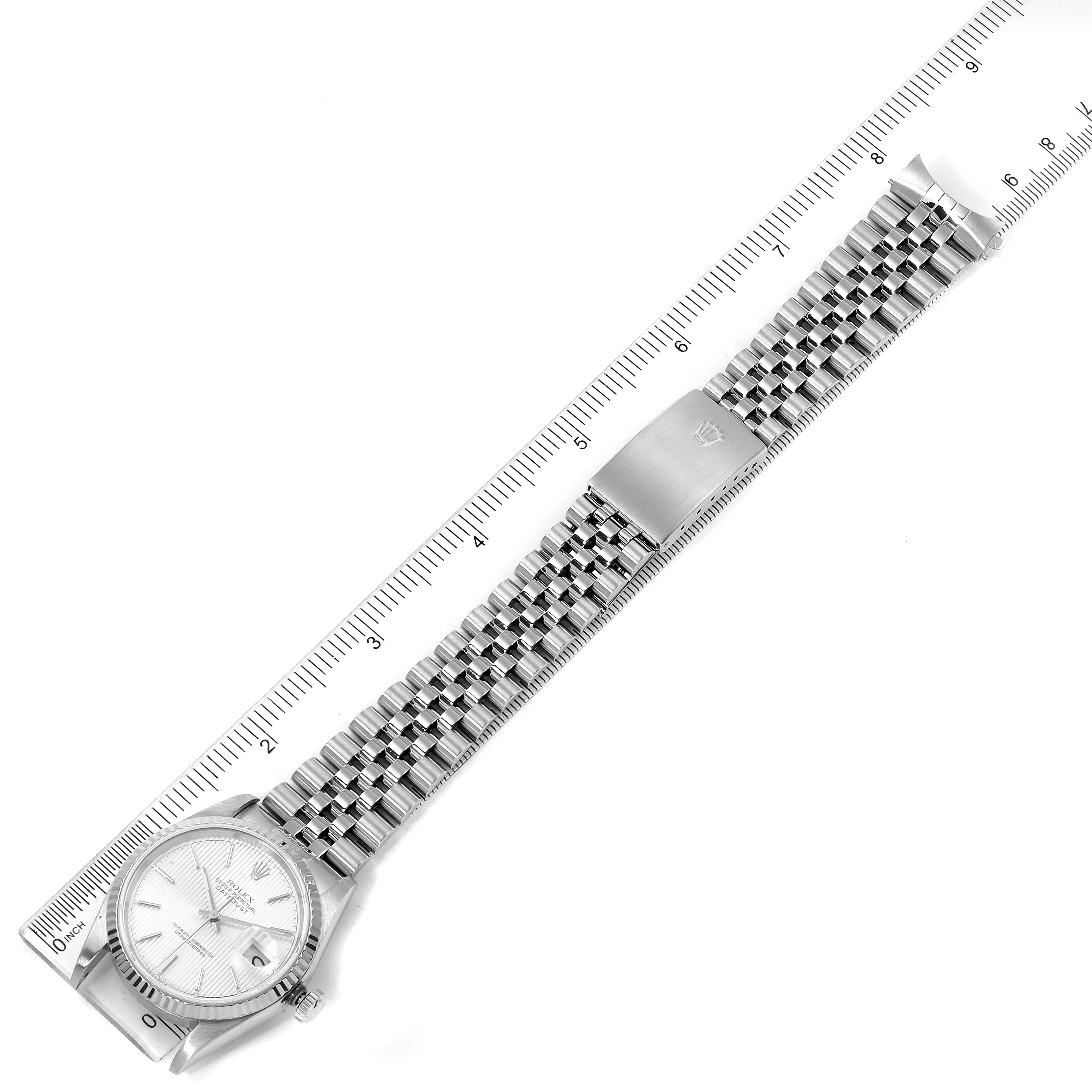 The Rolex Datejust 16234 Men's Stainless Steel Silver Dial 16234 Men's Stainless Steel Silver Dial watch is shown from a top-down angle, featuring its face, bracelet, and clasp laid flat against a ruler.