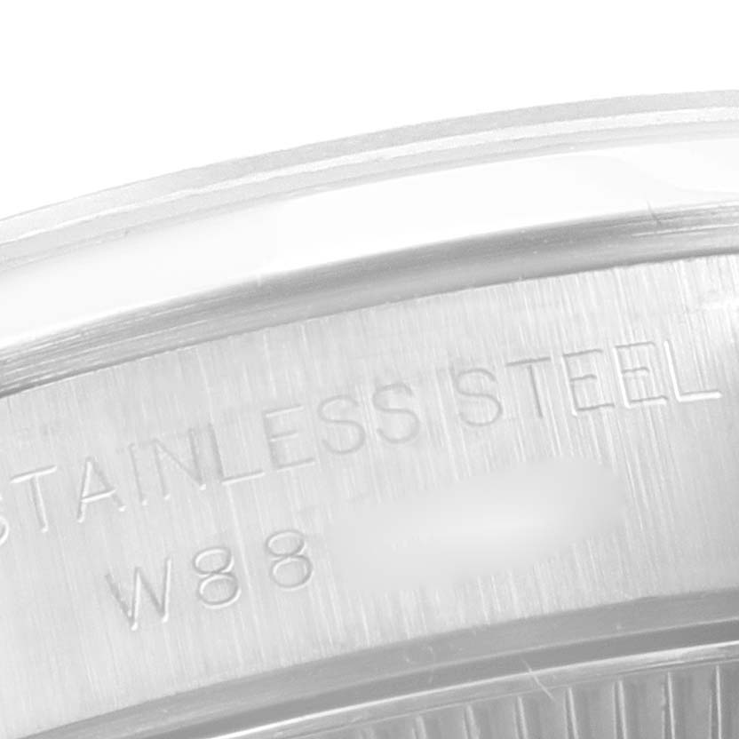 This close-up image of a Rolex Oyster Perpetual 67180 Women's Stainless Steel White Dial 67180 Women's Stainless Steel White Dial watch shows a section of the stainless steel case with engraved text.