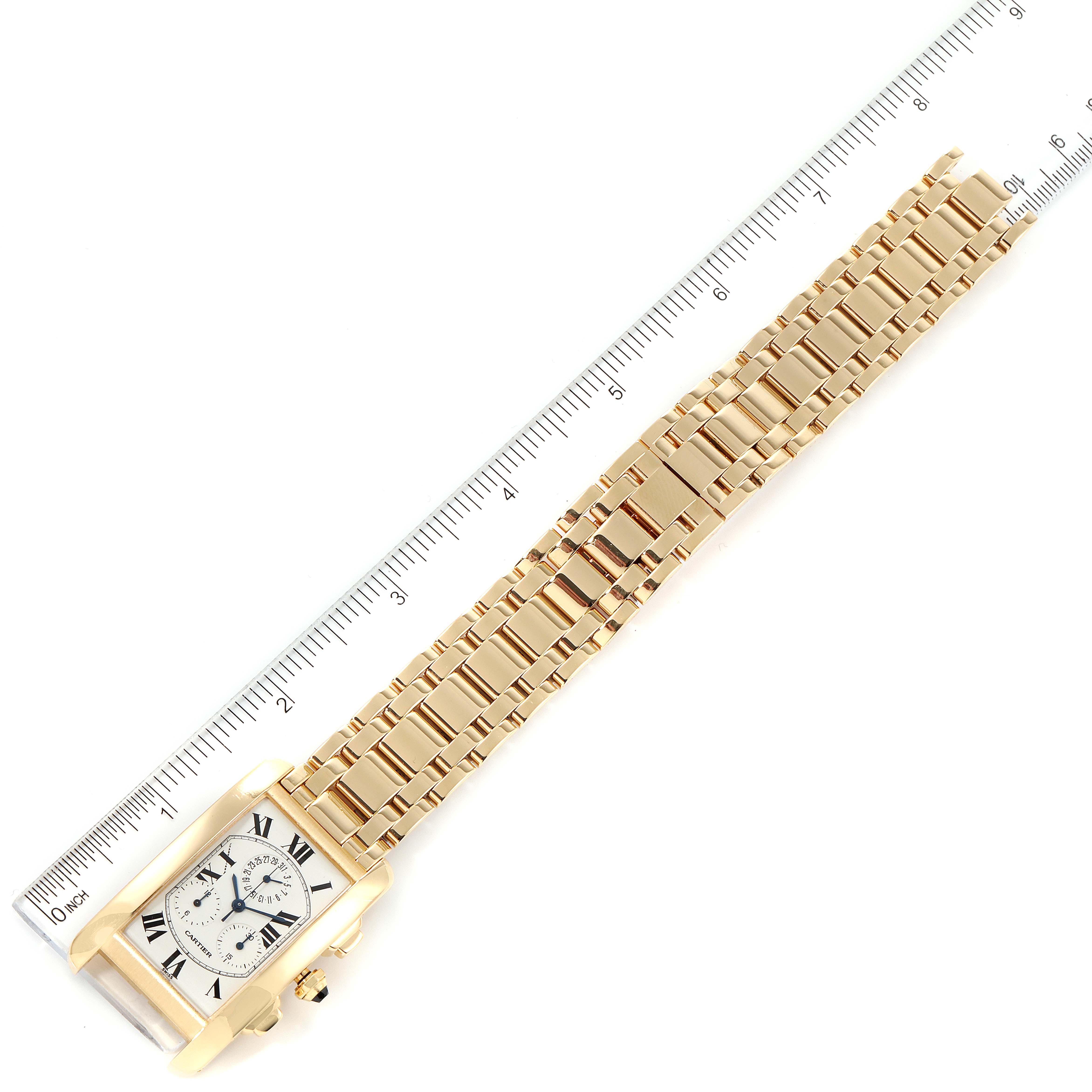 The image shows a Cartier Tank Americaine W2601156 Men's Yellow Gold Silver Dial W2601156 Men's Yellow Gold Silver Dial watch laid flat with a gold bracelet band and a ruler for scale.