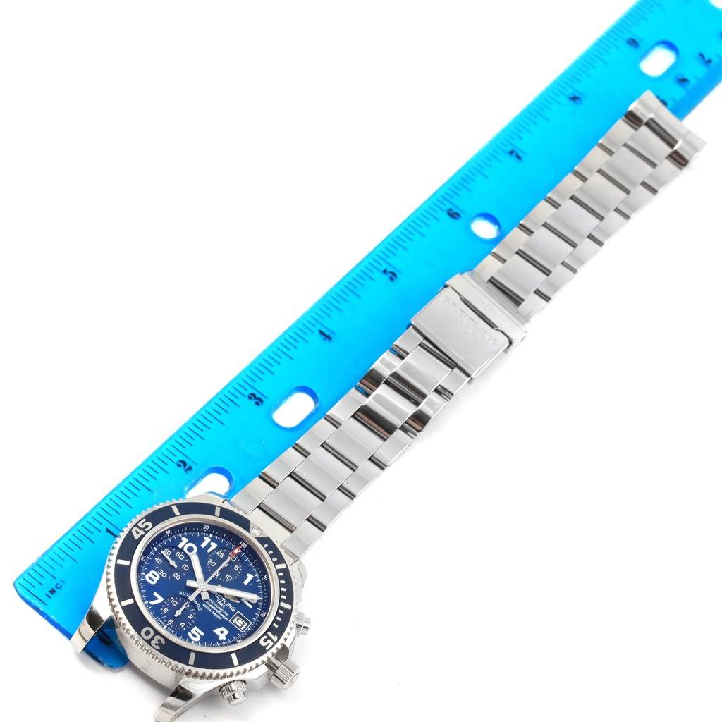 The image shows a top-down view of a Breitling Superocean A13311 Men's Stainless Steel Blue Dial A13311 Men's Stainless Steel Blue Dial watch with its metal bracelet placed alongside a blue ruler for measurement.