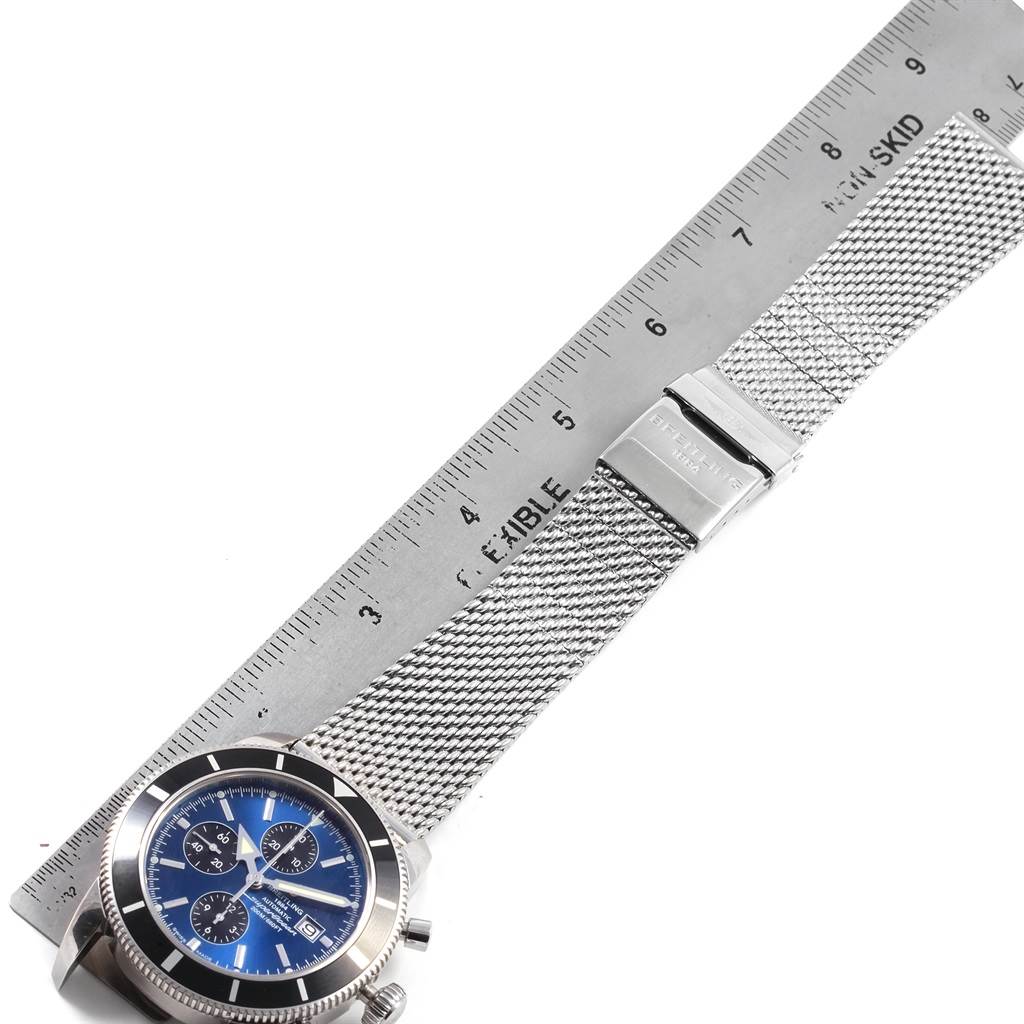 The Breitling Superocean A13320 Men's Stainless Steel Blue Dial A13320 Men's Stainless Steel Blue Dial watch is shown from a top-down angle, featuring the blue dial, bezel, and metal mesh strap with a clasp beside a ruler.
