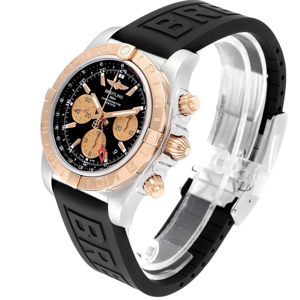 The Breitling Chronomat CB042012/BB86 Men's Steel and Gold (two tone) Black Dial CB042012/BB86 Men's Steel and Gold (two tone) Black Dial watch is shown from an angle highlighting the face, bezel, crown, pushers, and black rubber strap.