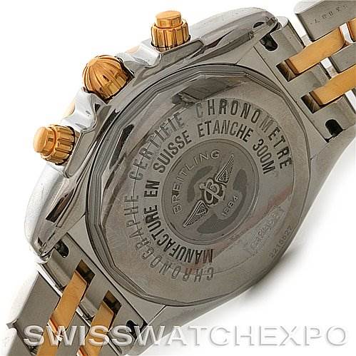 The image shows the back case and part of the bracelet of a Breitling Chronomat C1335611/K515-TT Men's Stainless Steel Burgundy Dial C1335611/K515-TT Men's Stainless Steel Burgundy Dial watch, emphasizing the engraved text and gold crown pushers.