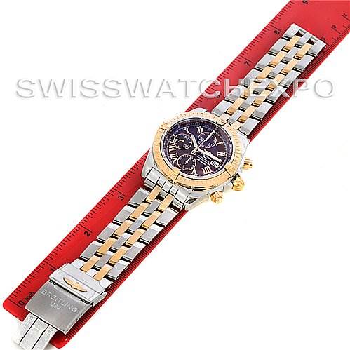 The image shows a top-down view of a Breitling Chronomat C1335611/K515-TT Men's Stainless Steel Burgundy Dial C1335611/K515-TT Men's Stainless Steel Burgundy Dial watch with a metal bracelet laid on a red ruler.