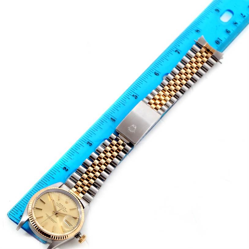 This image shows a top view of a Rolex Vintage Collection 16013 Men's Stainless Steel Champagne Dial 16013 Men's Stainless Steel Champagne Dial watch, including its face and two-tone metal bracelet, next to a ruler.