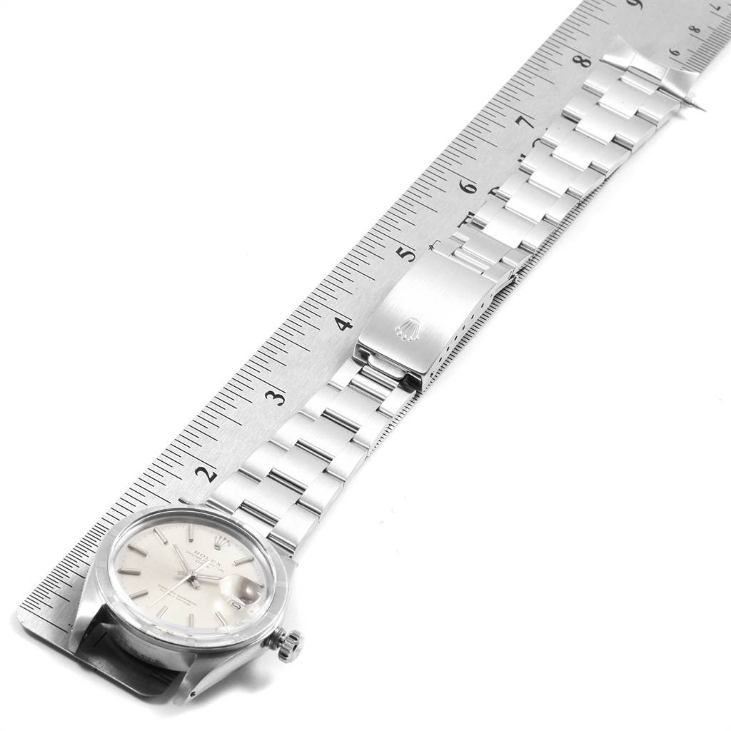 The image shows the side view of a Rolex Vintage Collection 1501 Men's Stainless Steel Silver Dial 1501 Men's Stainless Steel Silver Dial watch with its bracelet laid flat against a ruler.
