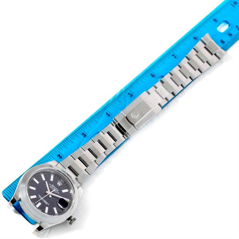 This image shows the Rolex Datejust 41 116300 Men's Stainless Steel Black Dial 116300 Men's Stainless Steel Black Dial watch laid flat, highlighting its face, bezel, and entire bracelet with a clasp next to a ruler.